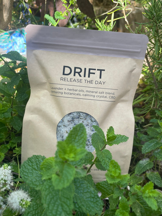 DRIFT: Release The Day – Soul Soaks bath blend in kraft pouch surrounded by fresh herbs